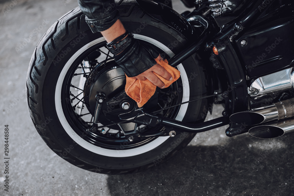 Cropped photo of man cleaning his motorbike with rag Cropped photo of man cleaning his motorbike with rag