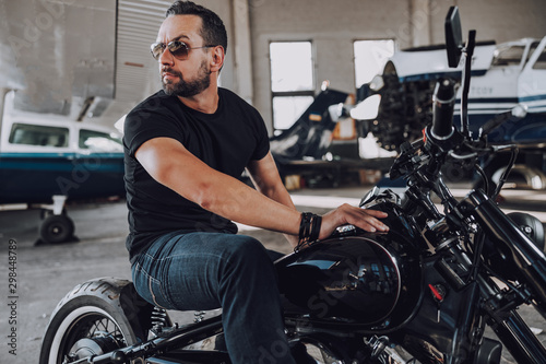 Caucasian handsome biker waiting for somebody in garage