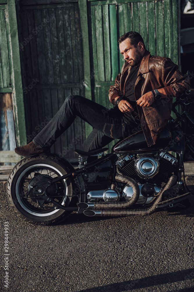 Naklejka premium Handsome biker is posing for camera outdoors