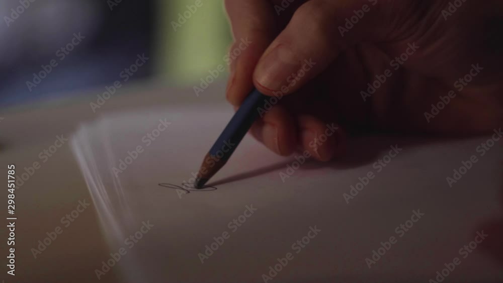 close up su mano che scrive una lettera con una matita su un foglio di carta