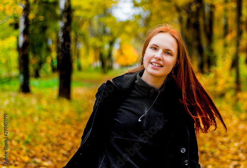 portrait of young teenager redhead girl with long hair in autumn park. 