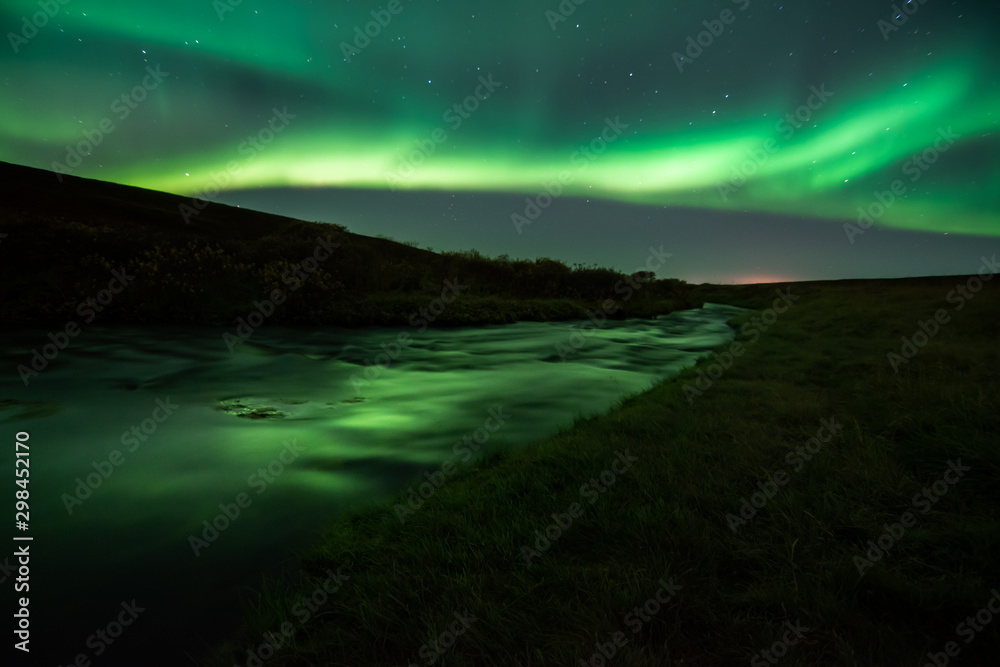 Fototapeta premium Northern lights with reflection in river, North Iceland