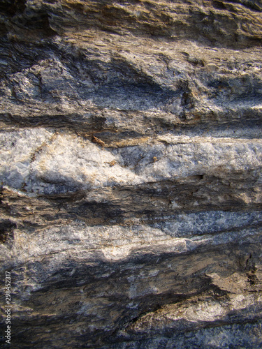 Rock formation with a layered gray-light structure. Vertical layout.