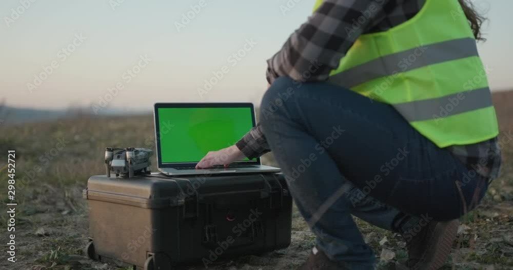 Working at the computer with green screen. Side view of male hands using touch pad of a working laptop with chromakey.