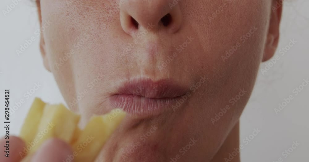 Woman eating french fries, unhealthy eating, close-up lips. Woman eating french fries, unhealthy eating, close-up lips.