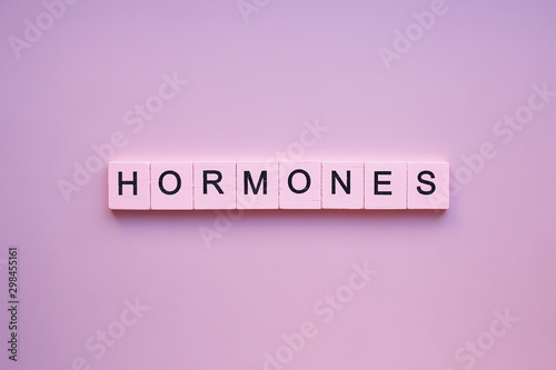 Hormones word wooden cubes on a pink background photo