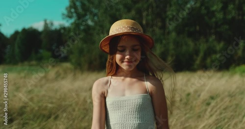 Cheerful preteen girl is in the field at Sunny Day. Child enjoy the sun. Slow motion