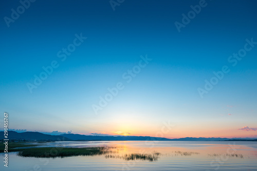 Calm Lake Sevan in Armenia in the rays of the rising sun from behind the mountains