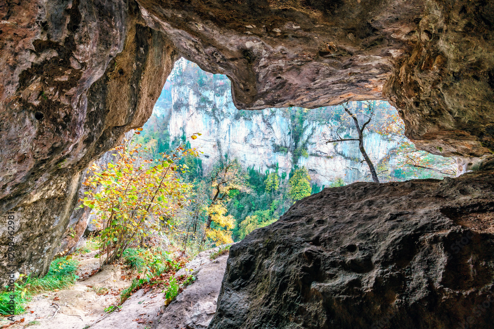 Beautiful scenic autumn landscape of Kurdzhips gorge viewed from inside rocky grotto at Palmoviy waterfall in Caucasus mountains by Mezmai, Russia