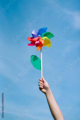 Hand holding pinwheel with blue sky background. © Chaithawach