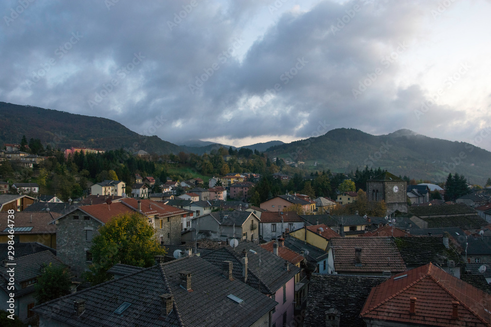 Fototapeta premium Panoramic view of a small village isolated in wild mountains, rainy autumn day with clouds