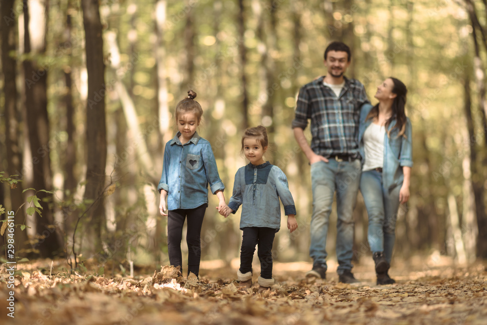 A young family walks in the autumn forest with children.