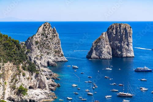 The Faraglioni are three scenic rocks emerging from the sea near Capri coastline, Italy photo