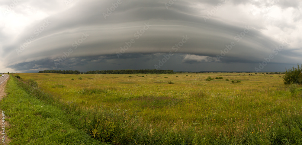 The photo was taken in the Ivanovo region of Russia. Over the field and the forest you can see the approach of a huge storm front.