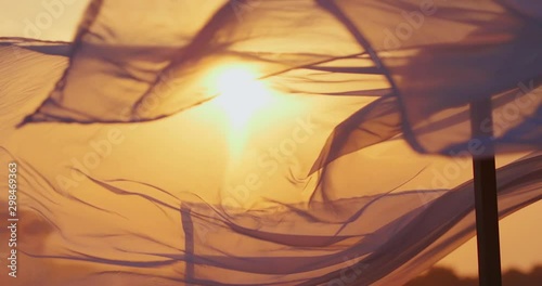 Gazebo on the beach by the sea. Sand beach. Curtains develop in the wind. Evening light summer