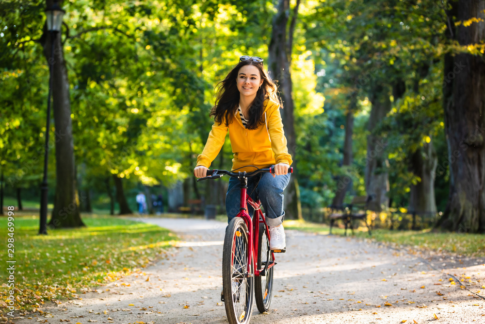 Urban biking - woman riding bike in city park - obrazy, fototapety, plakaty 