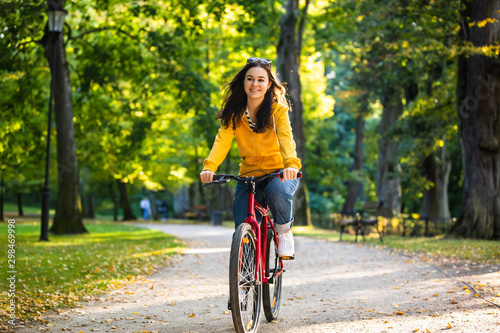 Fototapeta Urban biking - woman riding bike in city park