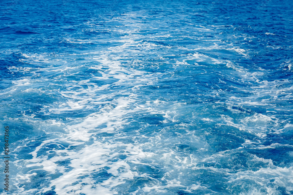 Obraz premium Blue sea surface background with splashing waves