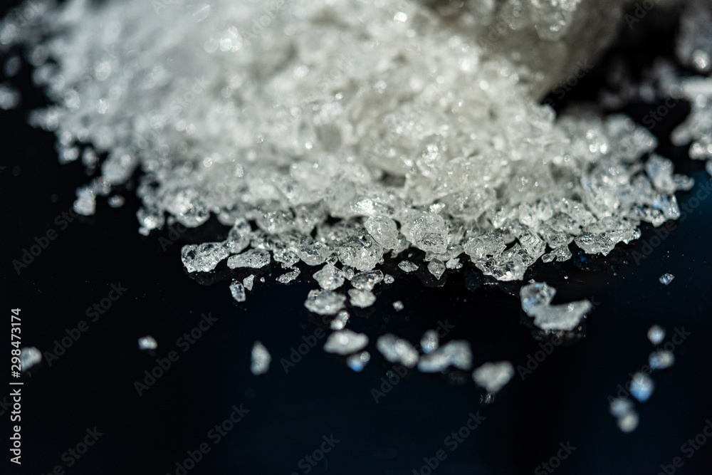 Large crystal of salt on black reflective surface; selective focus; natural edible salt Large crystal of salt on black reflective surface; selective focus; natural edible salt