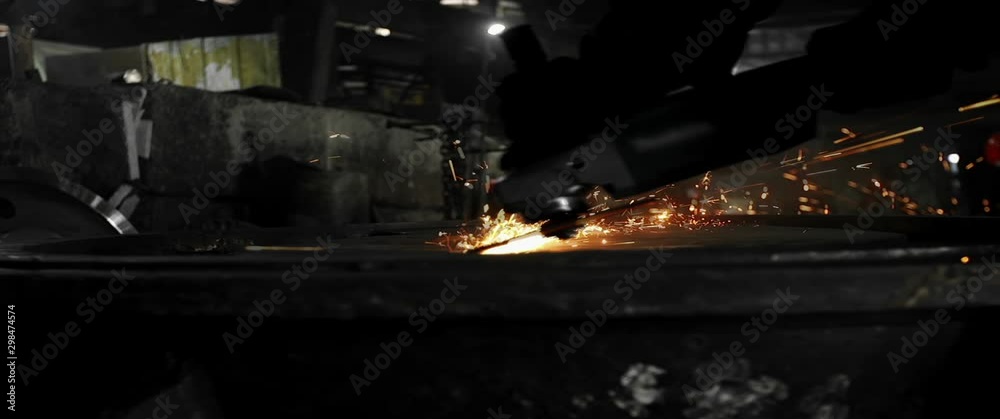 Male hand cuts off pieces of water pipe with angle grinder. Cutting of a steel with splashes of sparks at construction site. Sparks during cutting of metal angle grinder Male hand cuts off pieces of water pipe with angle grinder. Cutting of a steel with splashes of sparks at construction site. Sparks during cutting of metal angle grinder