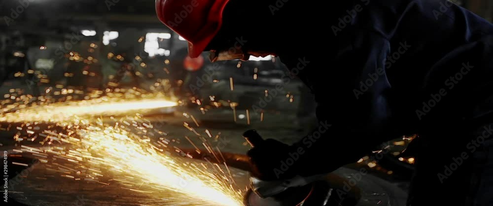 Male hand cuts off pieces of water pipe with angle grinder. Cutting of a steel with splashes of sparks at construction site. Sparks during cutting of metal angle grinder
