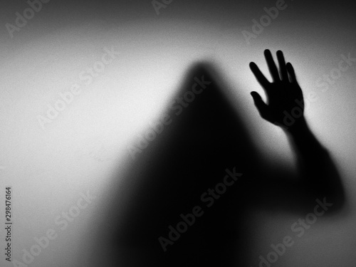 The scary black shadow is behind the glass. Halloween concept.
