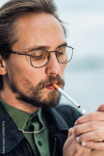 Young handsome man lighting up cigarette