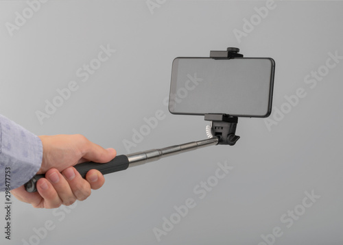 hand holds selfie stick with phone with screen clipping path