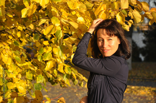 Beautiful young woman on a background of a tree crown with yellow leaves.