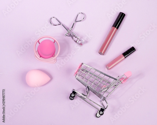 Pastel make-up tool included blender sponge brush eyelash curler on purple background