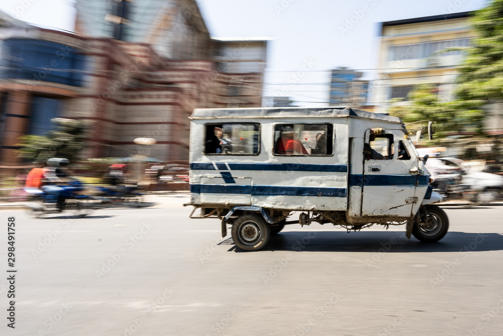 Motor rickshaw is riding fast with passengers through Kathmandu streets.