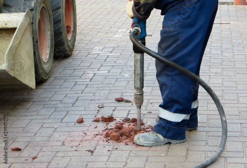 Worker crushes paving slabs with a jackhammer