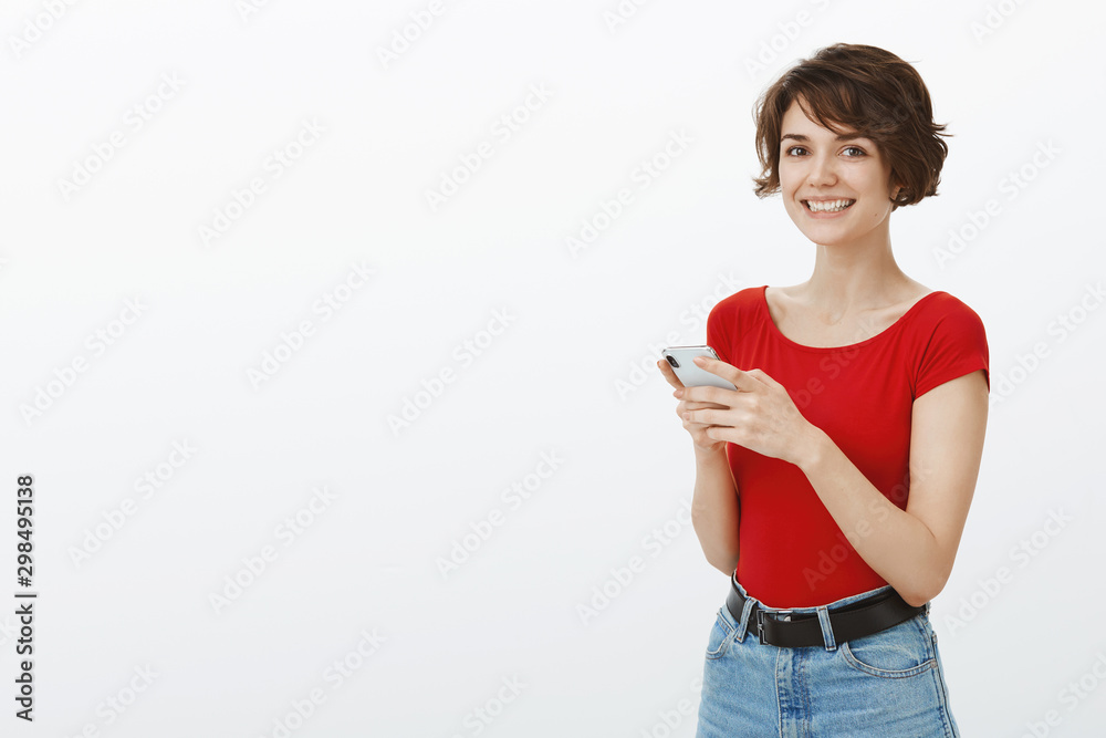 Happy charismatic young woman short stylish haircut standing half-turned hold smartphone turn camera smiling white teeth optimistic lucky mood freelance smm blogger write new post social media Happy charismatic young woman short stylish haircut standing half-turned hold smartphone turn camera smiling white teeth optimistic lucky mood freelance smm blogger write new post social media