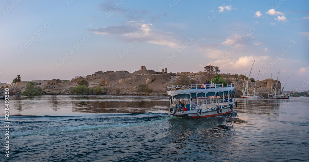 Touristic boat and Elephantine island in background with old egyptian ruins, Aswan, Egypt Touristic boat and Elephantine island in background with old egyptian ruins, Aswan, Egypt