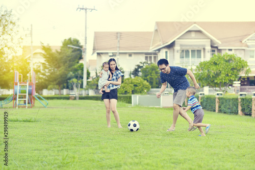 Portrait of Asian family playing football together in garden