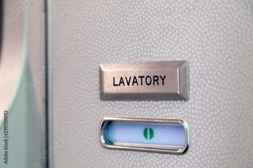 Vacant green sign, vacant symbol on an airplane lavatory door. Raised, brushed metal lavatory sign, recessed plastic vacant sign. Toilet room, wc, closet on airplane board