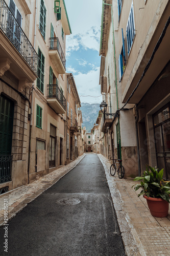 Fototapeta Naklejka Na Ścianę i Meble -  An alley surrounded by old houses, with an old bicycle, and plants in the picturesque village of Soller, Mallorca, Spain. Vertical photo.