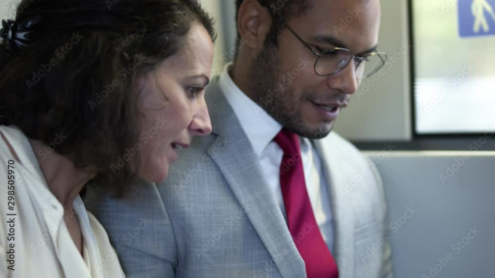 Smiling business people working in train. Close-up view of multiethnic businessman and businesswoman sitting together and discussing work in train. Business trip concept Smiling business people working in train. Close-up view of multiethnic businessman and businesswoman sitting together and discussing work in train. Business trip concept