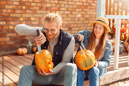 Halloween Preparaton Concept. Young couple outdoors making jack-o'-lantern carving pumpkins smiling concentrated