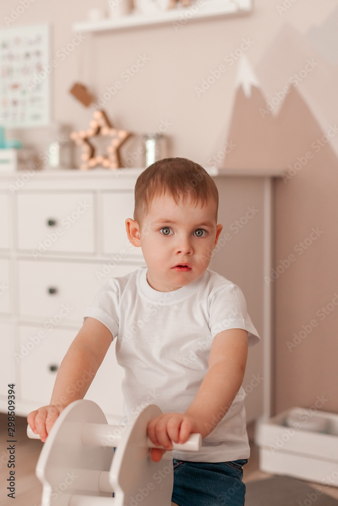 Cheerful boy Toddler baby swinging on a rocking chair in the shape of a horse Cheerful boy Toddler baby swinging on a rocking chair in the shape of a horse