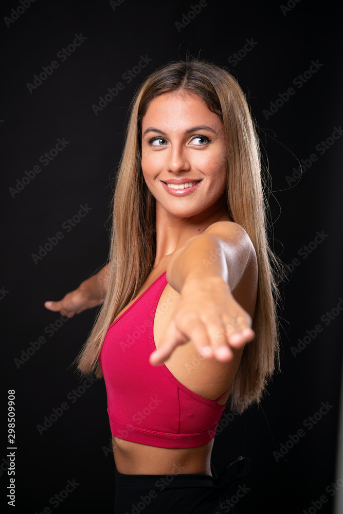 Young sport blonde woman over isolated black background Young sport blonde woman over isolated black background