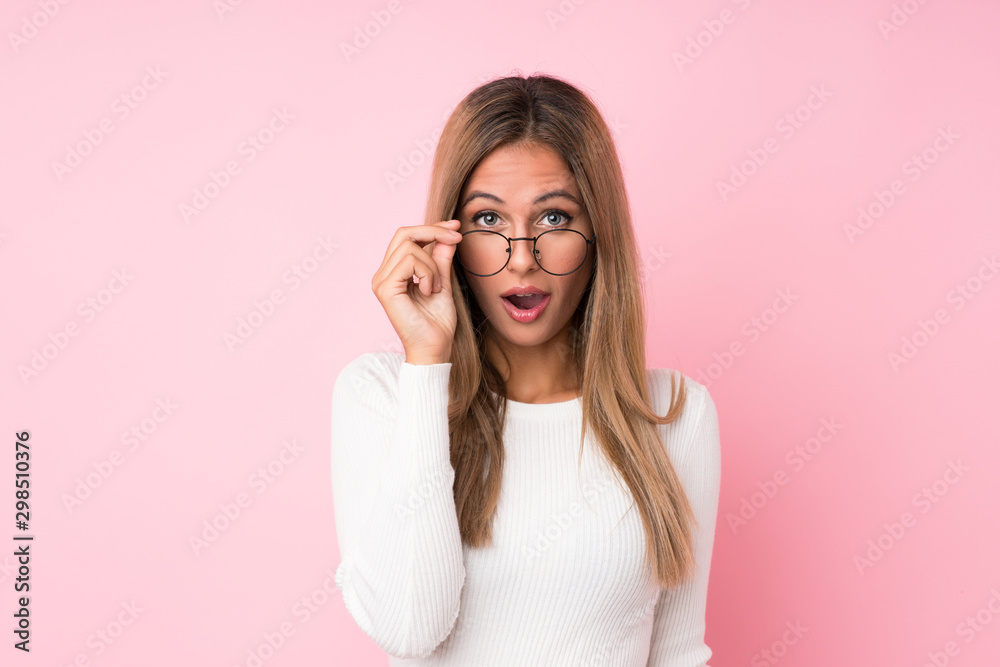 Young blonde woman over isolated pink background with glasses