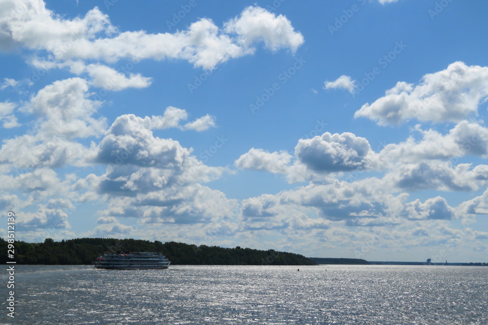 Russian beautiful Volga river landscape, floating passenger cruise ship on water and blue sky with clouds background on Sunny summer day