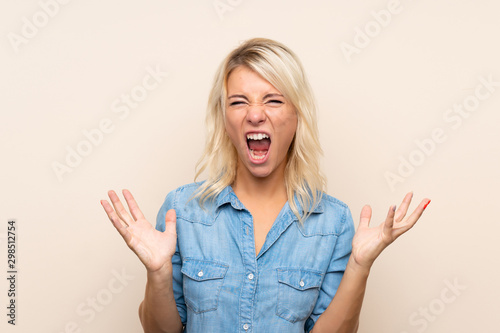 Young blonde woman over isolated background unhappy and frustrated with something