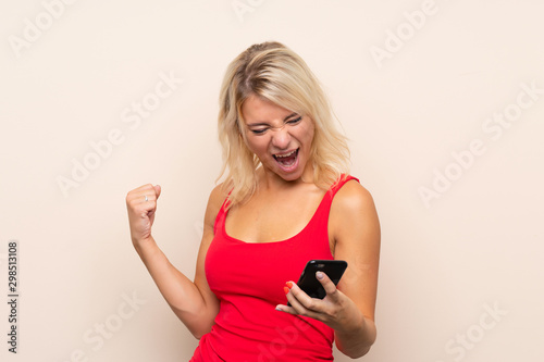 Young blonde woman over isolated background using mobile phone