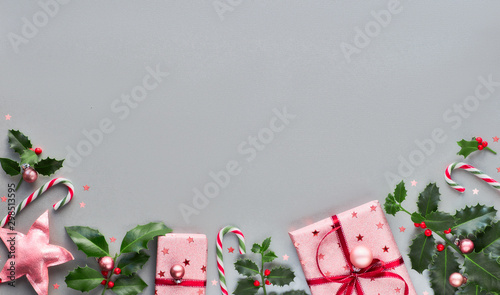 Festive Christmas background with pink gift boxes, stripy candy canes, trinkets and decorative stars, geometric creative flat layout on grey paper with copy-space © tilialucida
