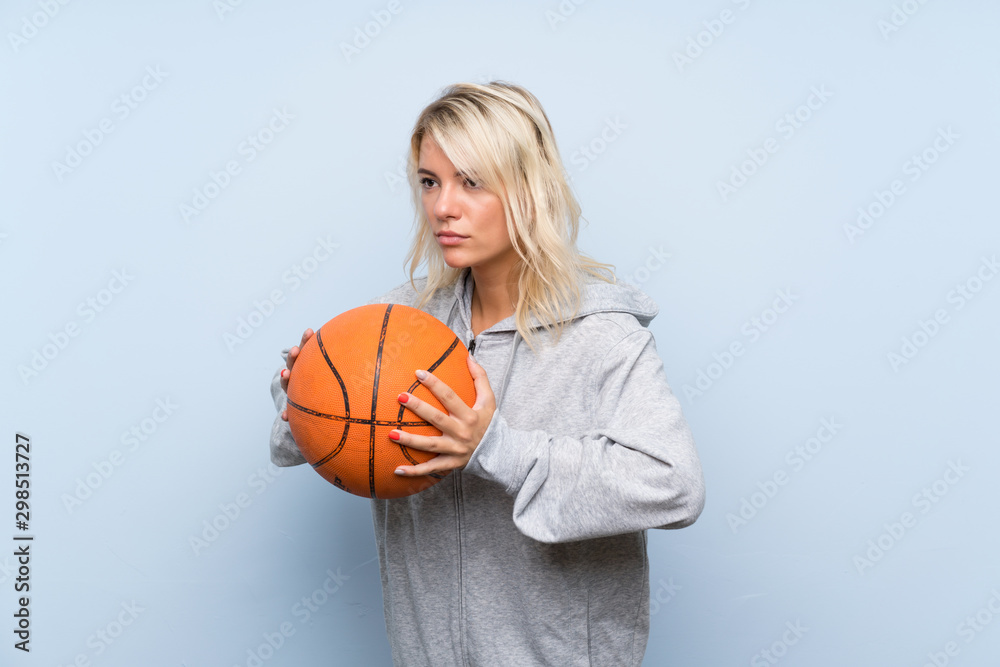 Young blonde woman over isolated background with ball of basketball Young blonde woman over isolated background with ball of basketball
