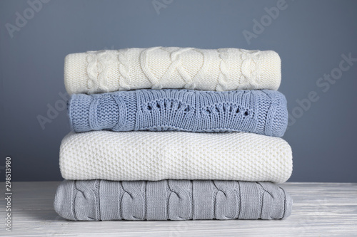 Fototapeta Naklejka Na Ścianę i Meble -  Stack of folded knitted sweaters on white wooden table against grey background