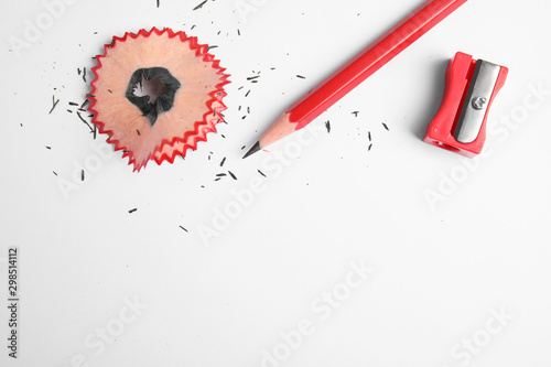 Pencil, sharpener and shaving on white background, top view