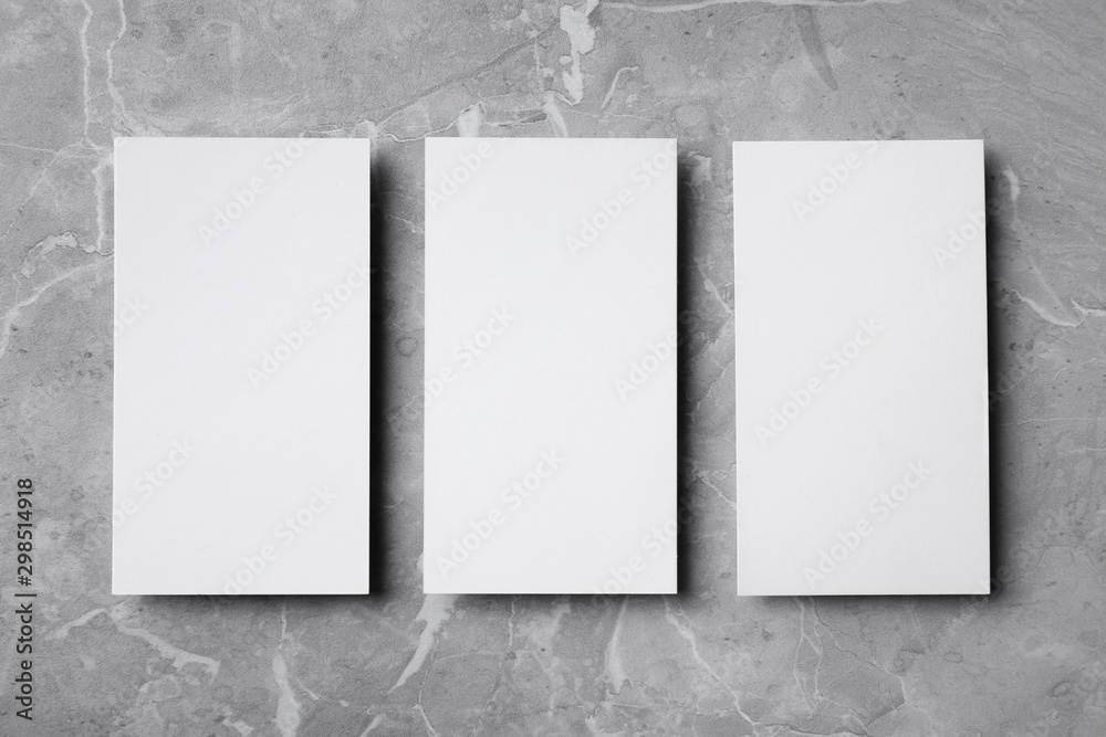 Empty sheets on grey marble table, flat lay. Mock up for design